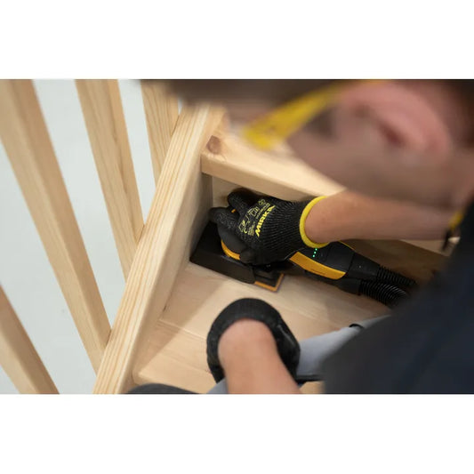Mirka DEOS Kantenschutz 81 x 133 mm wird an Holzkante angebracht, Handschuhe sichtbar, Schutz vor Beschädigungen.