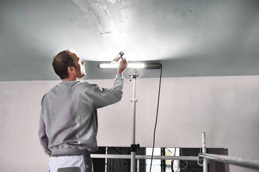 Festool SYSLITE STL 450 Streiflicht bei Oberflächenkontrolle auf Baustelle mit LED-Leuchte an Stativ