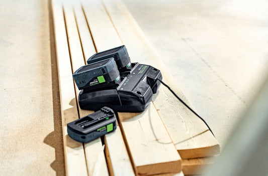 Festool Energie-Set SYS 18V mit zwei BP 18 Li 5,0 HP-ASI Akkupacks und TCL 6 DUO Schnellladegerät auf Holzdielen.
