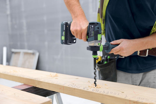 Festool Akku-Bohrmaschine mit zwei TBX4 Akkupacks beim Bohren in Holz auf der Baustelle