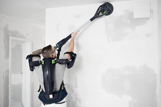 Festool ExoActive EXO 18-Basic Exoskelett bei Über-Kopf-Arbeiten an Wand mit Unterstützungssystem in Anwendung.