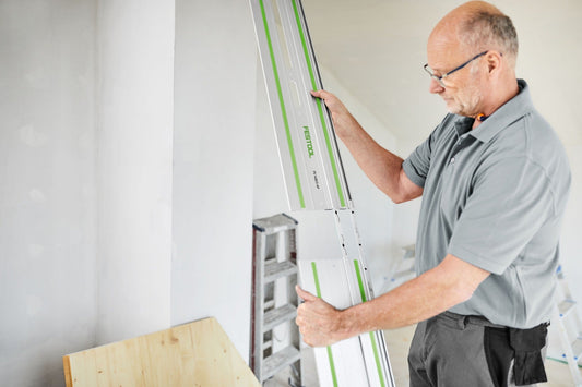 Festool Führungsschiene mit grünem Streifen bei Anwendung an Wand für präzise Schnitte