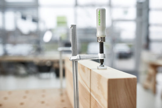 Festool Schraubzwinge FSZ 300 auf Holzwerkstück montiert, Ganzstahlausführung mit Holzgriff sichtbar.