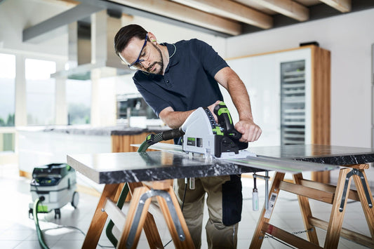 Festool Absaugmobil CLEANTEC CTL 26 EI in Anwendung beim Schneiden von Sperrholz mit Handkreissäge auf Werkbank.