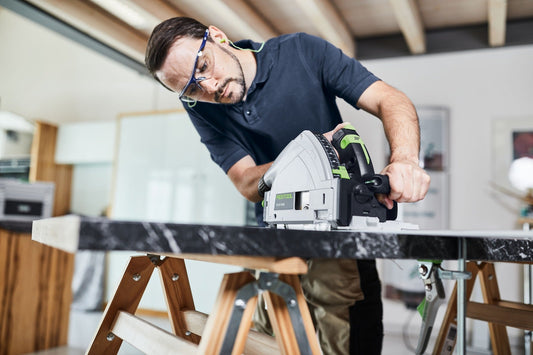 Festool Kreissäge mit Sägeblatt bei Holzschnitt auf Werkstück, Handwerker mit Schutzbrille in Werkstatt