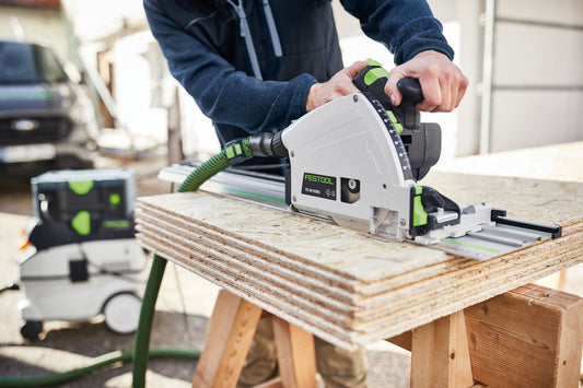 Festool Tauchsäge TS 60 KEBQ schneidet präzise in Sperrholzplatte auf Werkbank mit grünem Absaugschlauch