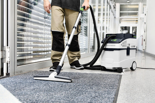 Festool CT 25 CLEANTEC Absaugmobil bei Reinigungsarbeiten auf grauem Teppichboden mit Saugschlauch