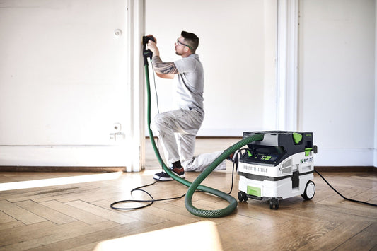 Festool CTL MINI I Absaugmobil in Anwendung beim Schleifen an Wand mit grünem Saugschlauch