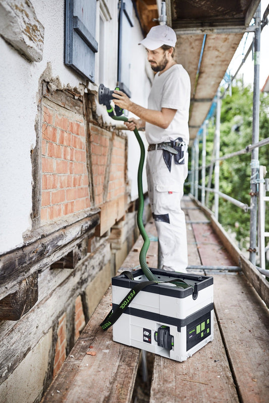 Festool CTMC SYS I-Basic Akku-Absaugmobil bei Sanierungsarbeiten an Außenwand, Handwerker mit Absaugschlauch.