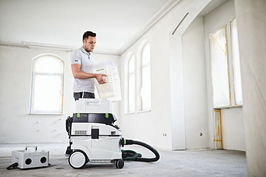 Festool CT Vorabscheider CT-VA-20 mit Zyklon-Technologie in leerer Baustelle, Mann entnimmt Auffangbehälter