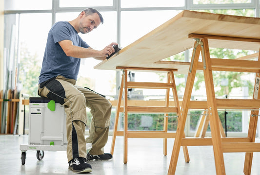 Festool Sitzkissen SK-CT/SYS in Anwendung, Handwerker sitzt ergonomisch auf Kissen beim Schleifen von Holzplatte