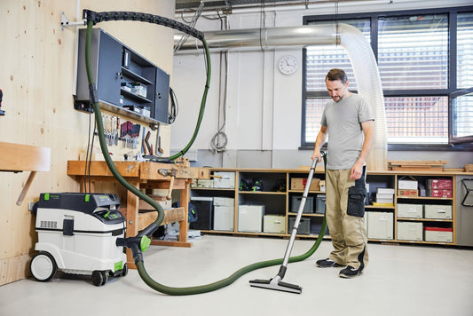 Festool Absauganlage mit Y-Ventil SV-AS D50 SWT im Einsatz, Mann bedient Schleifer mit Saugschlauch in Werkstatt.