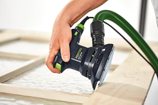 Festool Deltaschleifer DTS 400 REQ-Plus bei Anwendung auf Holzplatte, grüner Schlauch, Eckenschleifer in Hand