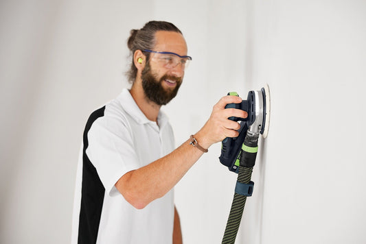 Festool Akku-Exzenterschleifer ETSC 2 150 in Anwendung an Wandfläche mit LED-Lichtring und ergonomischem Griff