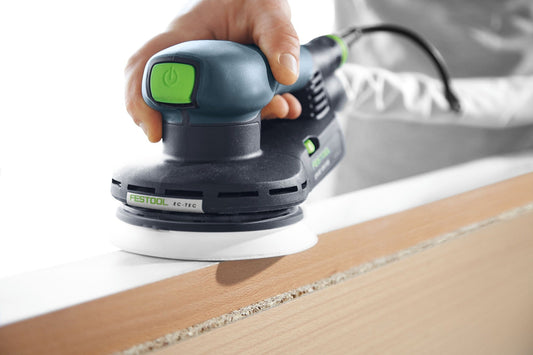 Festool ETS EC 125/3 EQ-Plus Exzenterschleifer mit grünem Power-Schalter beim Schleifen auf Holzoberfläche