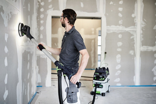 Festool Elektroschleiffer mit Schleifteller beim Schleifen von Gipskartonwand in Baustelle mit Absauganlage