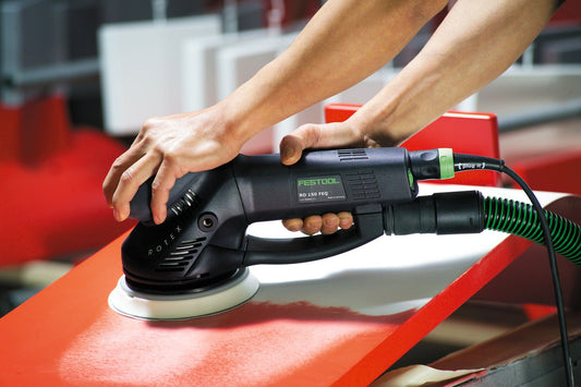 Festool RO 150 FEQ Rotex Schleifer mit Schleifscheibe bei der Anwendung auf orangefarbenem Werkstück