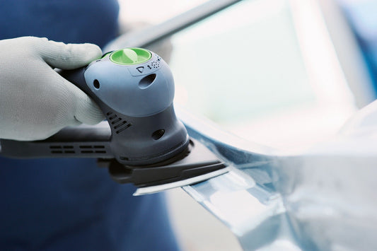 Festool Schleifschuh mit grünem Schleifteller und StickFix Klettbelag, in Schutzhandschuh gehaltene Detailansicht