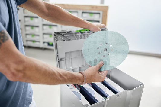 Festool Granat Net D225 Schleifscheibe mit Netzstruktur in der Hand über geöffnetem Systainer mit sortierten Körnungen