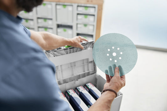 Festool Granat Net D225 Schleifscheibe mit Netzstruktur in der Hand, Systainer mit Körnungen im Hintergrund