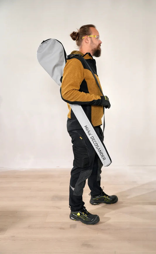 Handwerker trägt Mirka DecoSander 80x230 mm / 225 mm im praktischen Tragerucksack – komfortabler Transport für staubfreies Schleifwerkzeug auf Baustellen.
